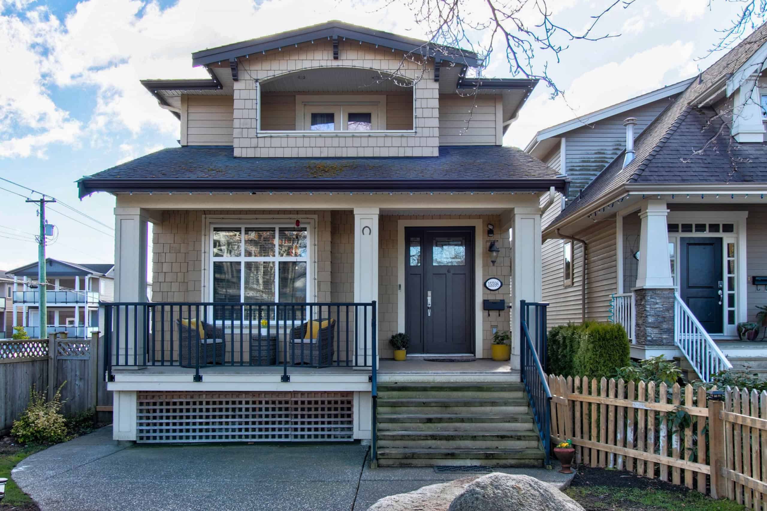 Charming Vancouver-style home featuring a spacious front porch, modern black door, and well-maintained landscaping, perfect for families and showcasing prime real estate in BC.