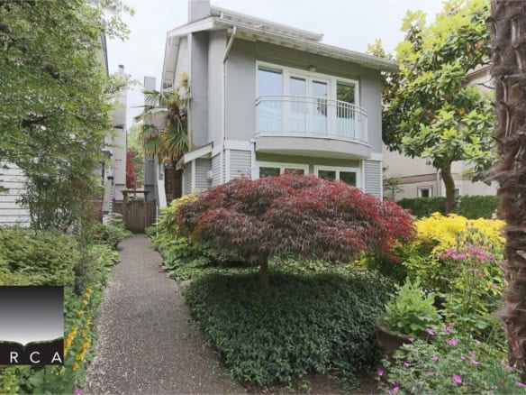 Lush garden leading to a modern two-storey house, emphasizing Vancouver Island real estate with beautiful landscaping and a serene outdoor space.