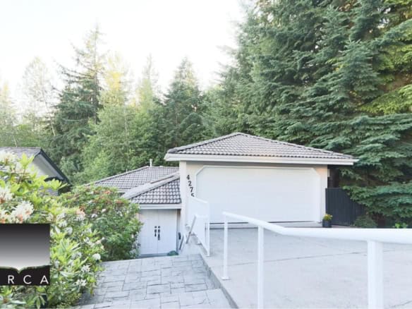 Modern white residential house with driveway and lush green trees, Vancouver real estate listing.