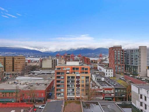 Vibrant cityscape view of downtown Vancouver with modern high-rise buildings and mountains in the background, showcasing urban real estate opportunities in British Columbia.