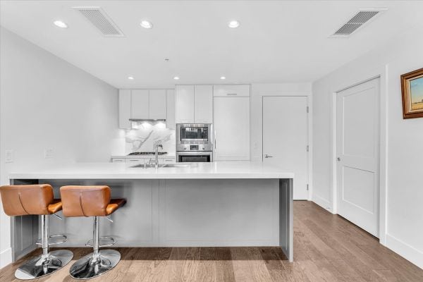 Contemporary kitchen in Vancouver featuring white cabinets, a sleek island, and modern appliances, perfect for stylish urban living.