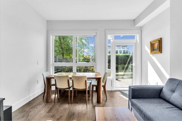 Bright Vancouver condo interior with large windows, dining area, and cozy seating, showcasing a stylish and inviting space at 101-7878 Granville Street.