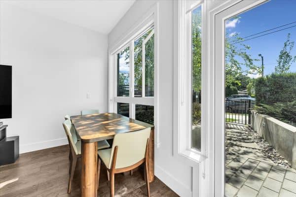 Bright dining space with large windows overlooking outdoor patio in Vancouver.