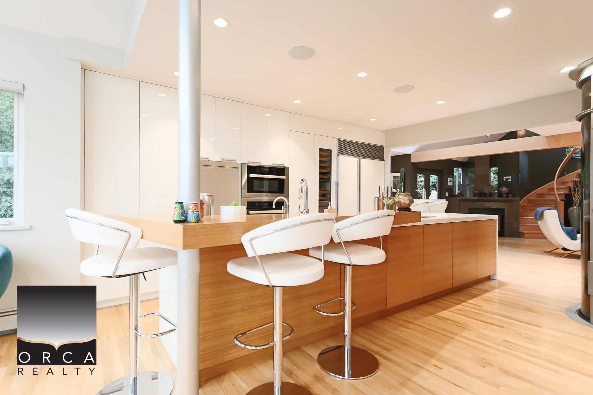 Modern open-concept kitchen with white cabinetry, wooden accents, and sleek appliances, ideal for Toronto real estate buyers seeking stylish homes.