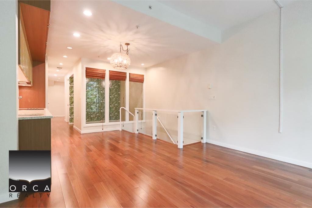 Spacious living area with hardwood floors, modern lighting, and large windows offering natural light, ideal for homebuyers seeking a comfortable and stylish interior.