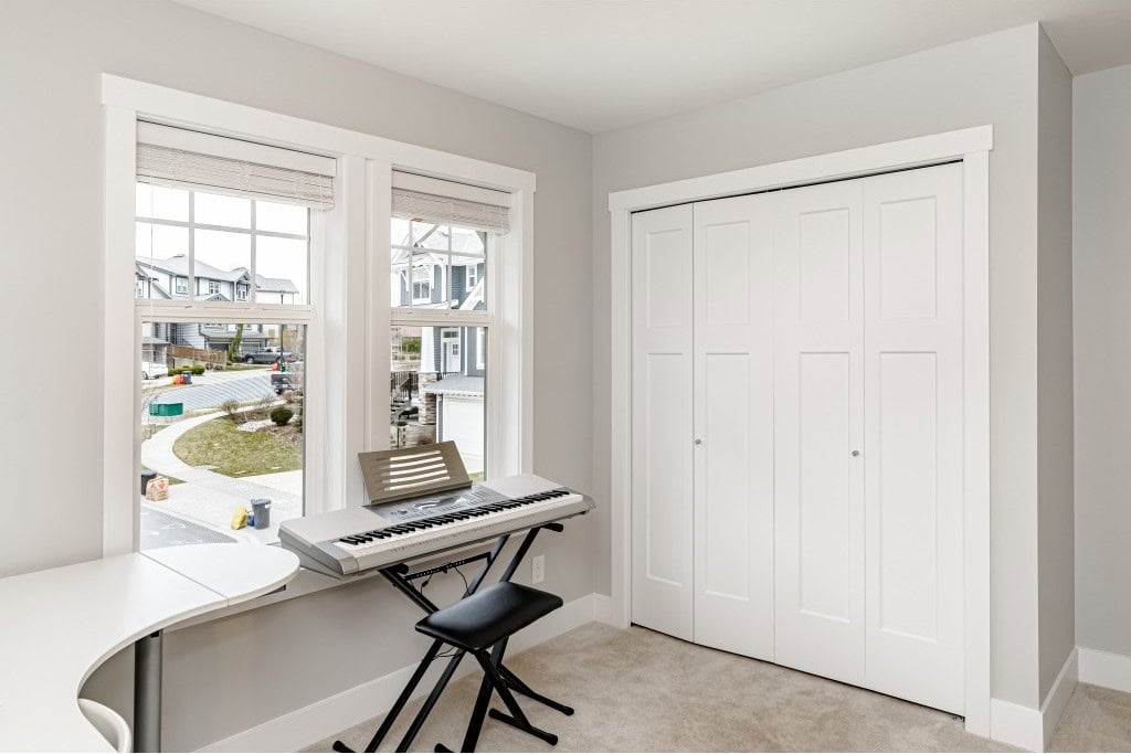 Bright home music room with electronic keyboard, white closet doors, and large windows in a modern residential interior.