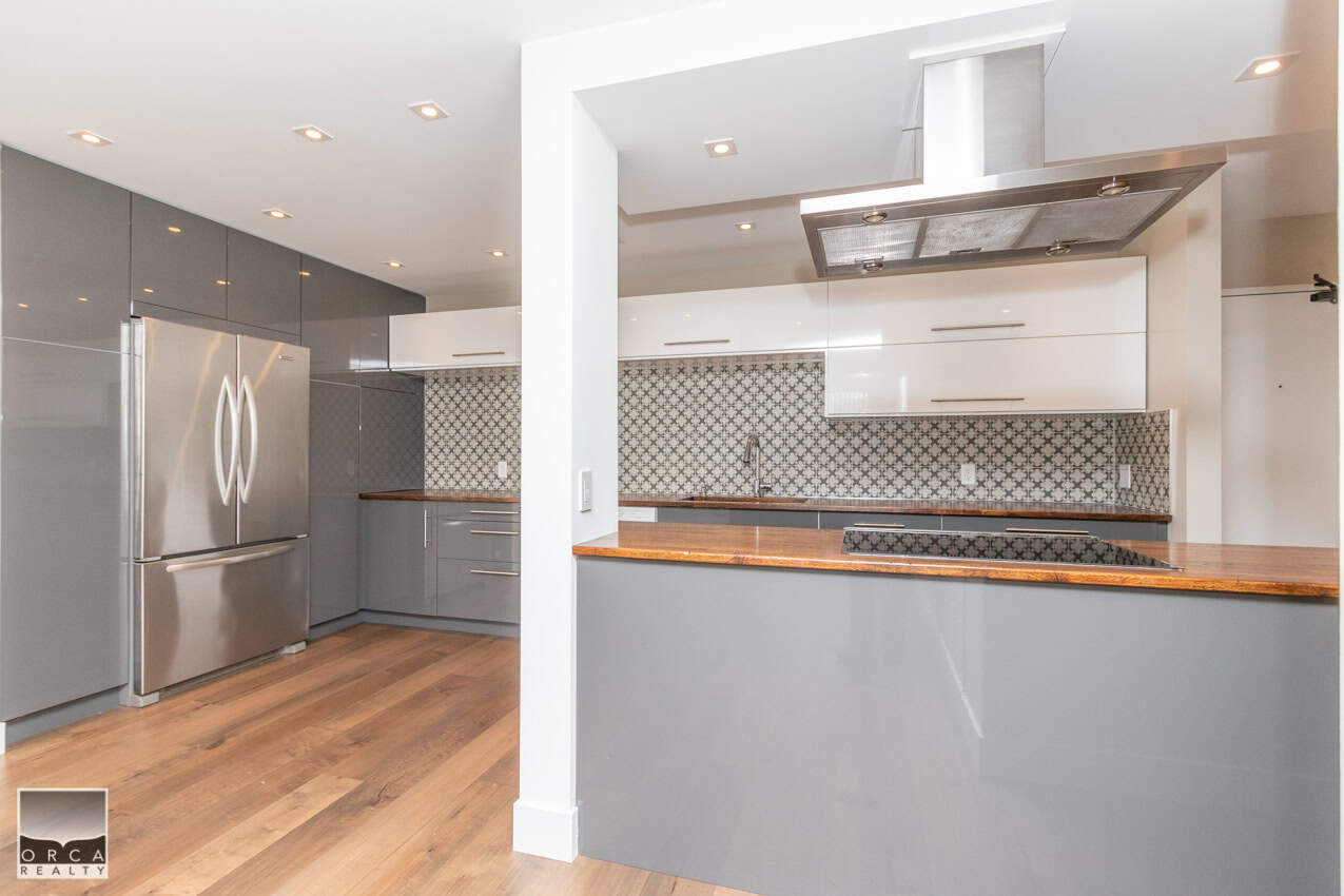 Modern grey and white kitchen with stainless steel appliances and patterned backsplash, featuring wooden countertops and open-concept design perfect for Toronto homebuyers.