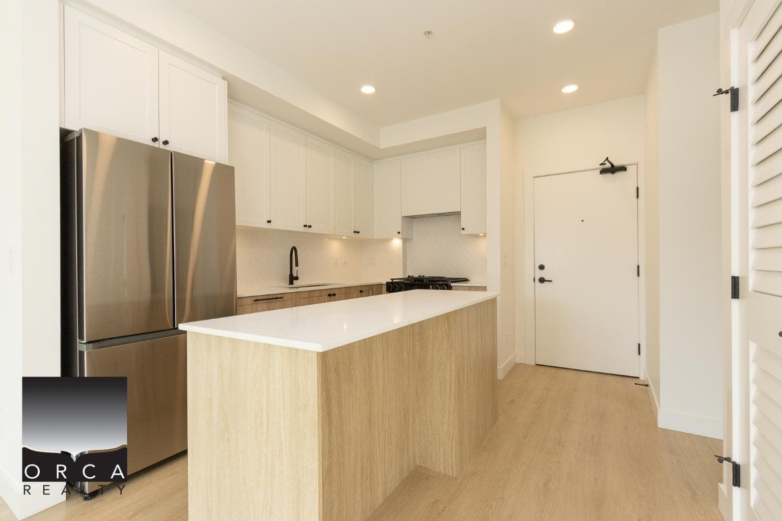 Contemporary kitchen with white cabinets, stainless steel refrigerator, and modern fixtures, perfect for Vancouver Island homes.