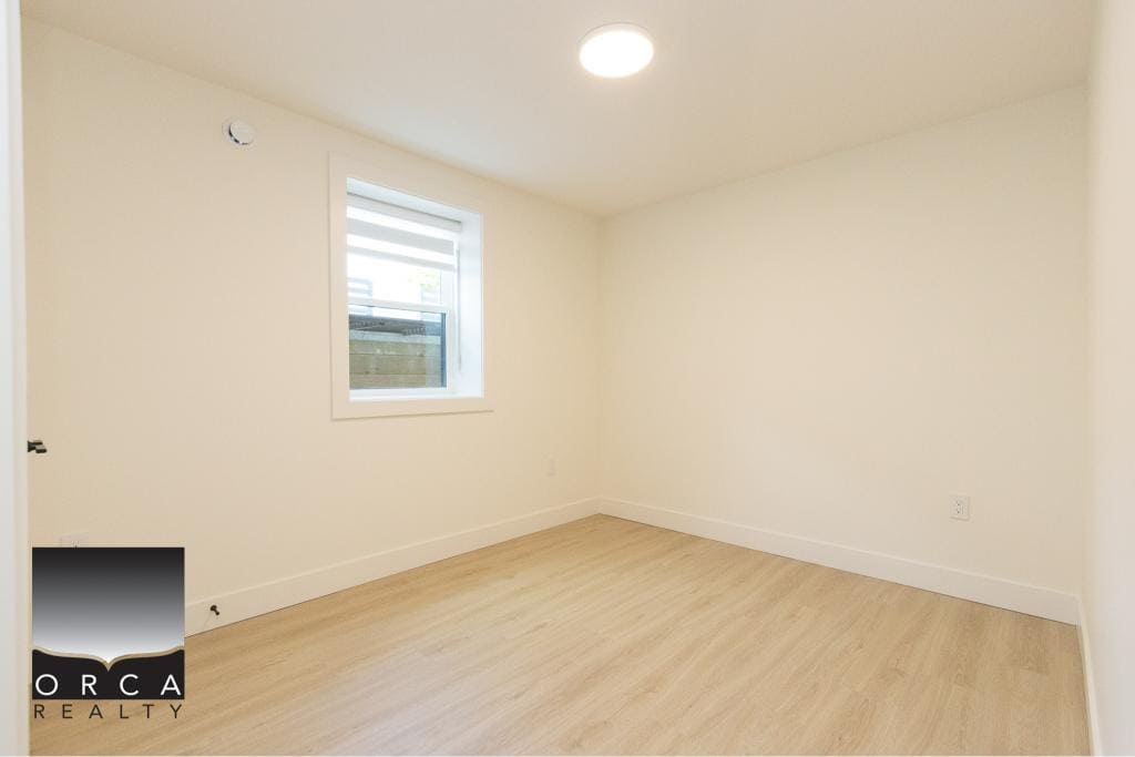Bright empty room with white walls and natural light from a window, ideal for home staging or real estate listings by Orca Realty Inc.