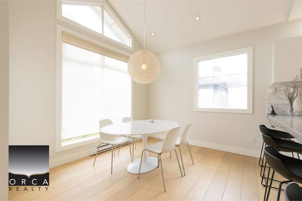 Bright modern dining room with large windows, white walls, and light wood flooring, perfect for a Vancouver Island home.