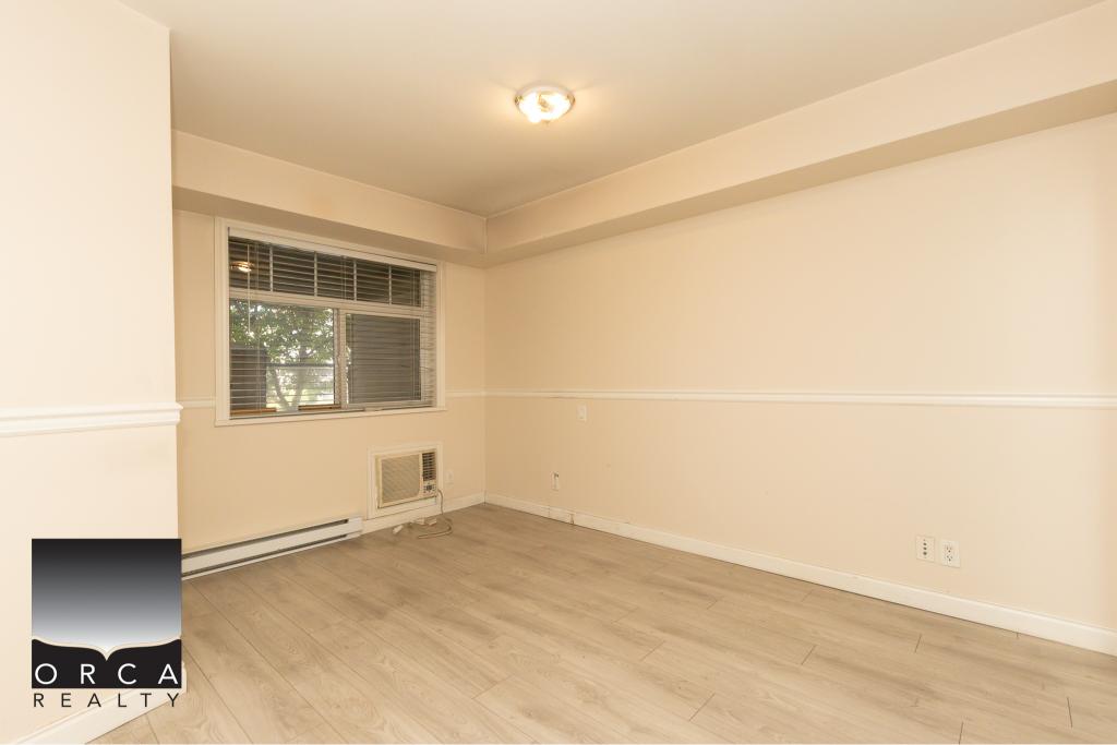 Bright empty room with large window, beige walls, and laminate flooring, ideal for home staging or renovations in Vacouver.