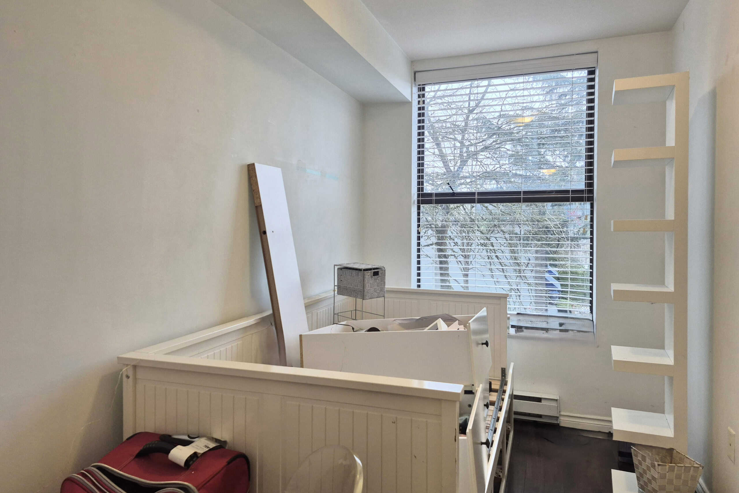 Bright nursery room with large window, white walls, and built-in shelving, ideal for family living in Vancouver. Perfect for real estate listings showcasing cozy and functional home spaces.