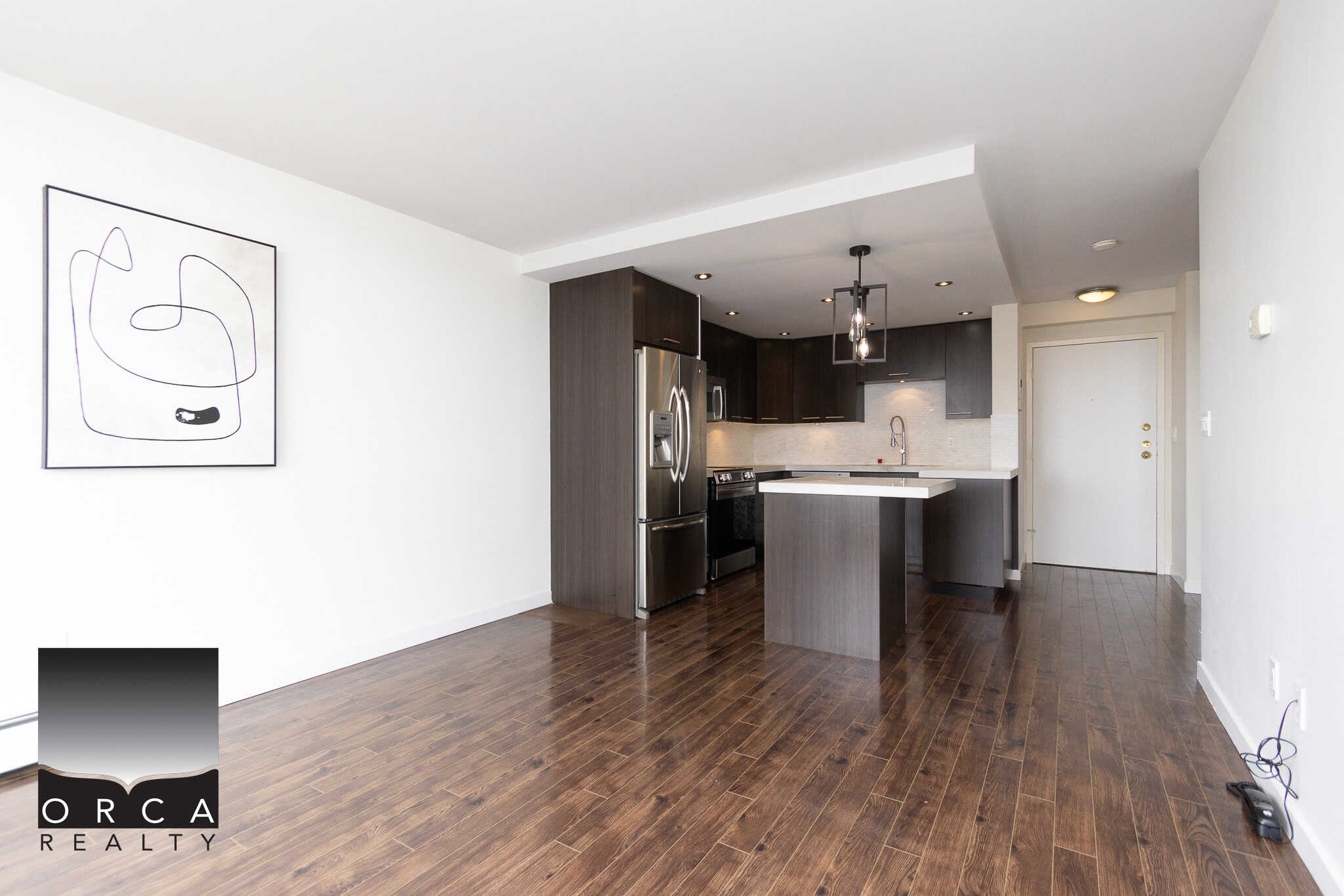 Modern kitchen interior with stainless steel appliances, dark wood cabinets, and open living space in a contemporary condo, ideal for homebuyers seeking stylish, functional properties.