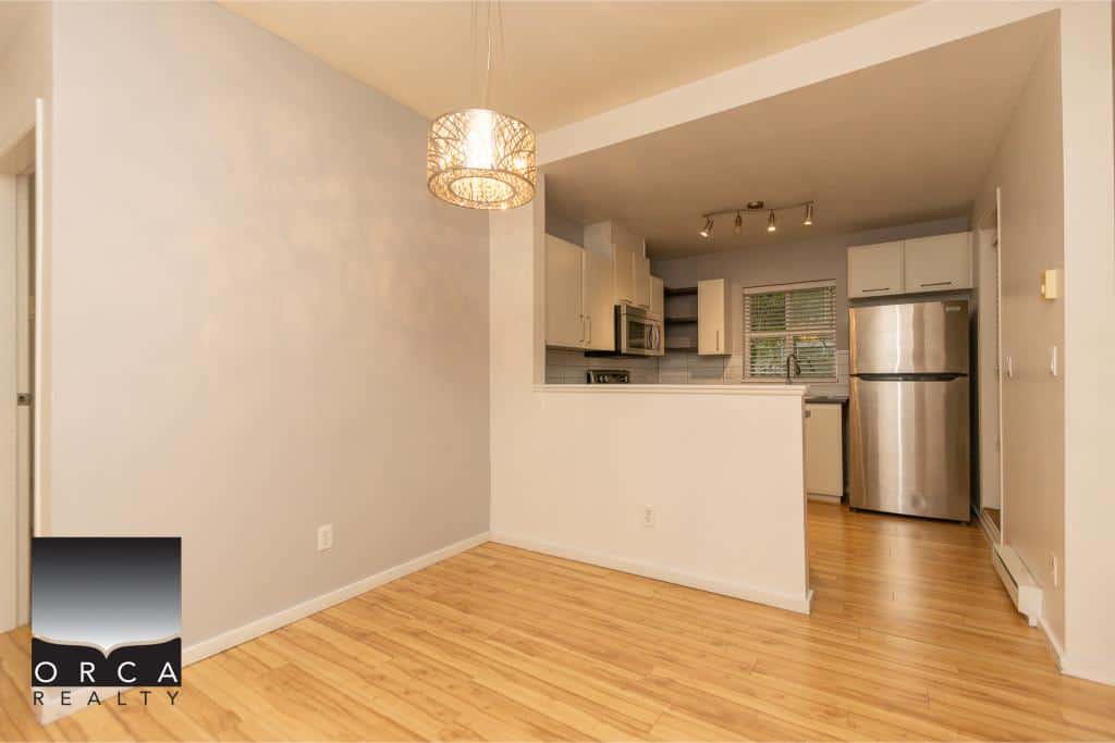 Bright open-concept kitchen and living area in a modern Vancouver home, featuring stainless steel appliances and hardwood floors. Perfect for comfortable living and entertaining.