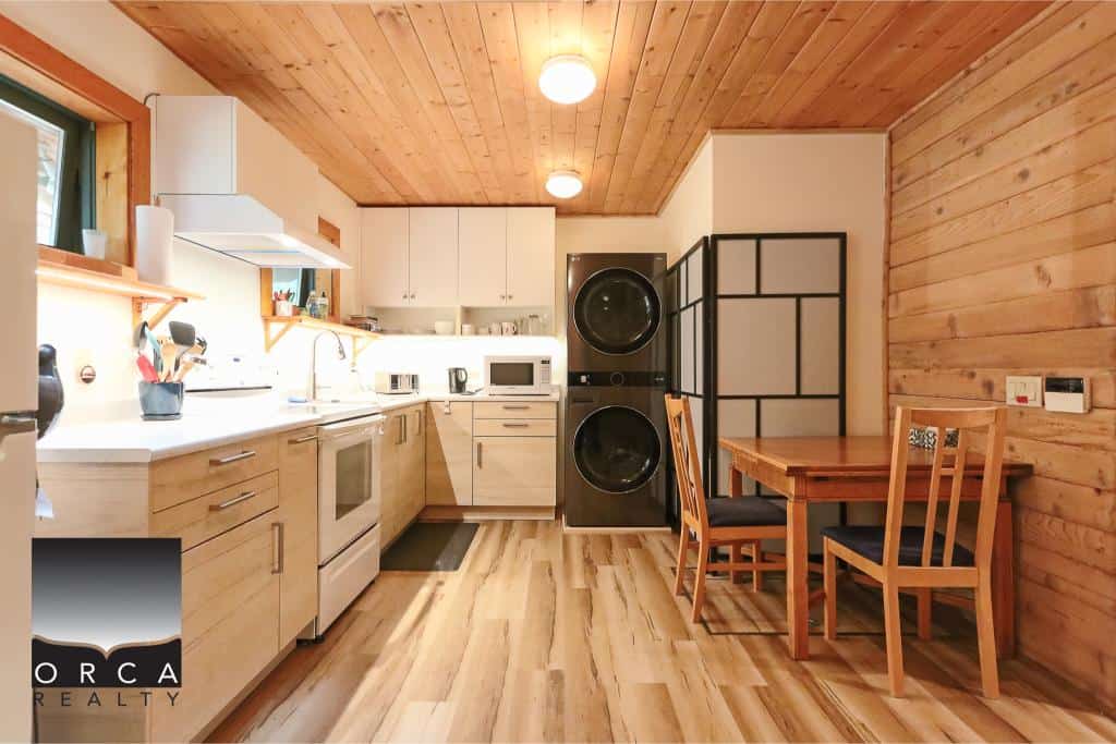 Cozy Vancouver Island kitchen with modern appliances, wood accents, and efficient laundry area, ideal for seamless real estate experiences in BC's scenic properties.