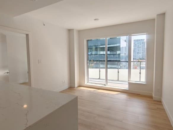 Bright modern apartment interior with large glass sliding doors, white walls, and light wood flooring, showcasing contemporary condo living in Vancouver.