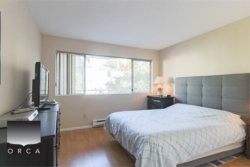 Cozy bedroom with large window, comfortable bed, and minimal decor, ideal for Vancouver area real estate listings.