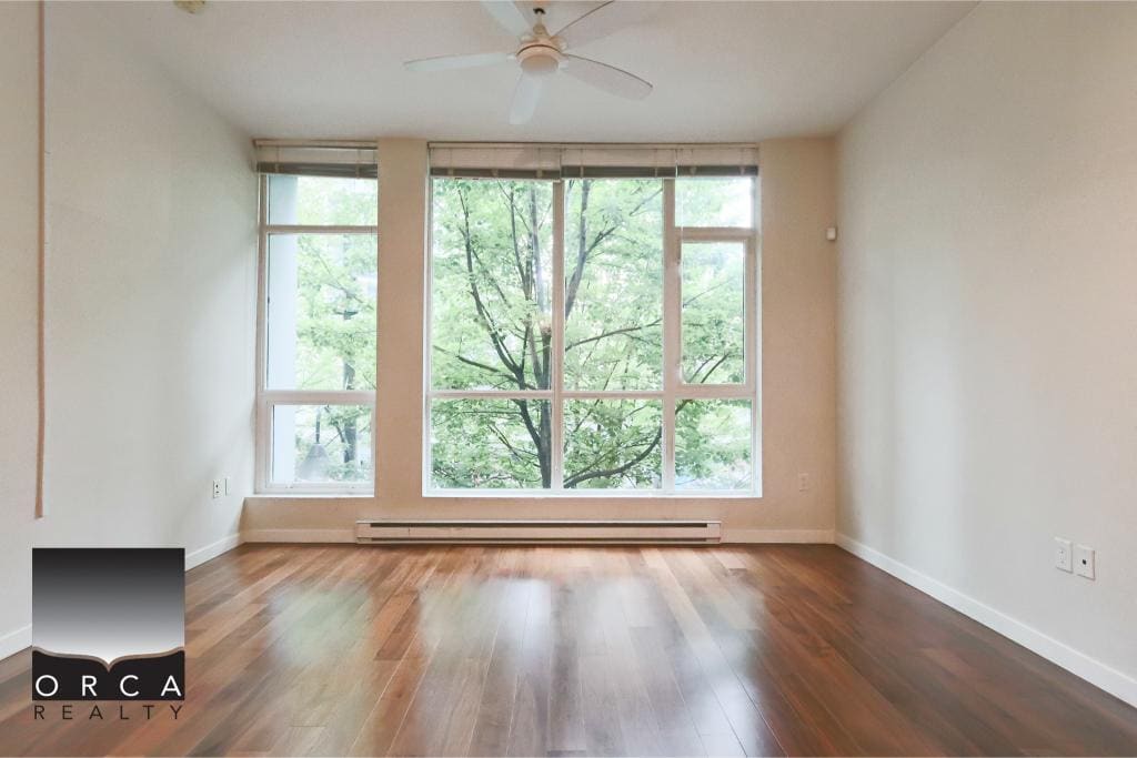 Bright empty apartment with large windows showcasing a lush green view, hardwood floors, and a minimalistic style, ideal for Vancouver real estate listings and home buyers seeking modern condos or apartments in the city.