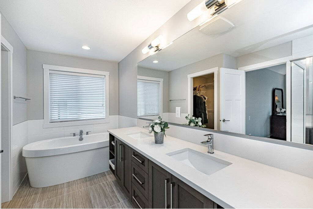 Modern bathroom with double vanity, large mirror, and a relaxing soaking tub, ideal for Vancouver Island real estate buyers seeking contemporary homes from Orca Realty Inc.
