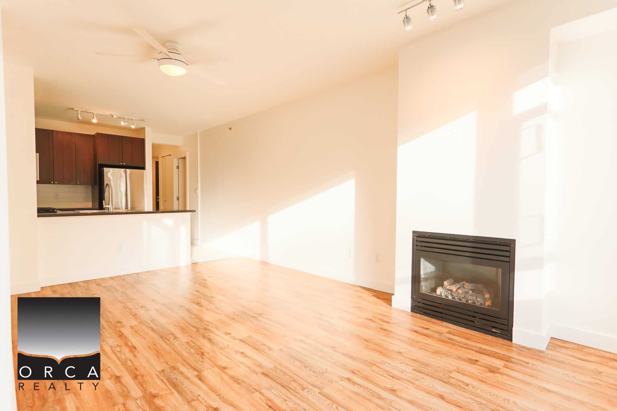 Bright and spacious North Vancouver condo featuring hardwood flooring, a cozy fireplace, and open living space, perfect for comfortable urban living at 203-170 W 1st Street.
