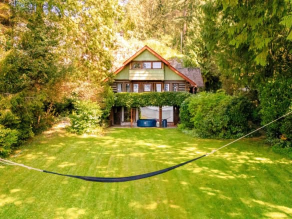 Lush backyard with well-maintained grass and mature trees, showcasing a charming house surrounded by greenery, ideal for outdoor living and gardening in Vancouver Island.