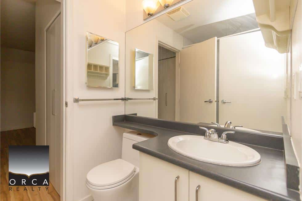 Clean bathroom with white fixtures, large mirror, and neutral decor, perfect for home buyers seeking a functional and stylish space.