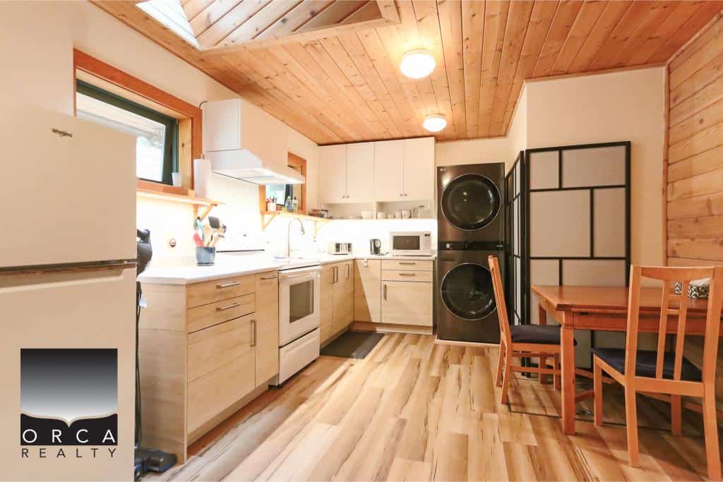 Modern kitchen with wood accents, appliances, and a dining area at Orca Realty Inc. showcasing cozy interior design and functional space for home buyers and renters.
