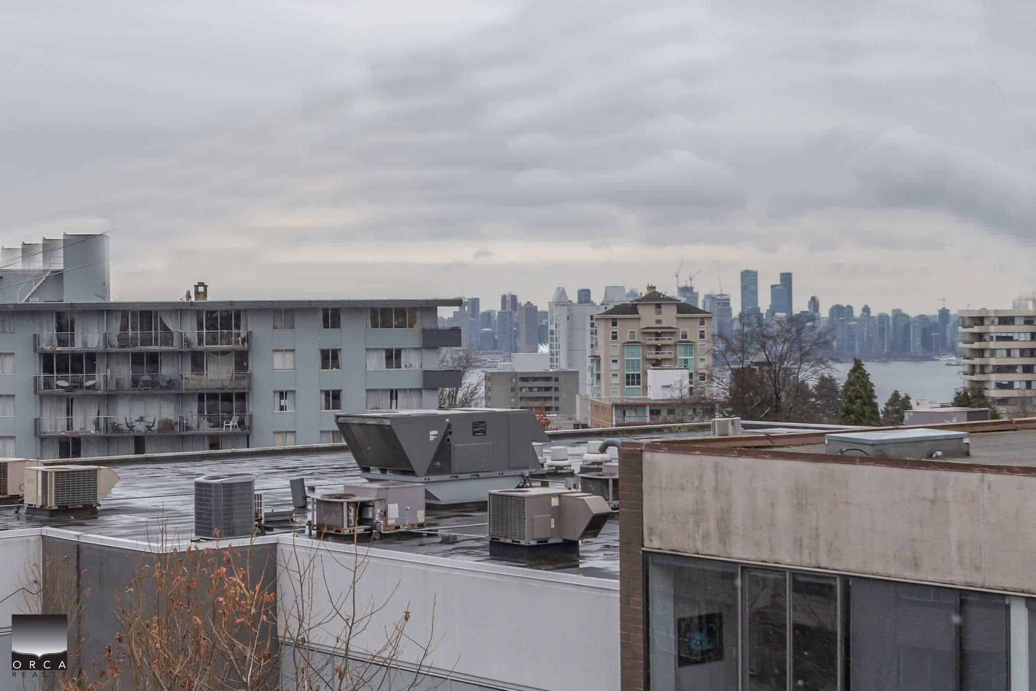 Modern urban rooftop with HVAC units and city skyline view, showcasing Vancouver’s cityscape, real estate development, and mountain backdrop, emphasizing expert commercial and residential real estate services.