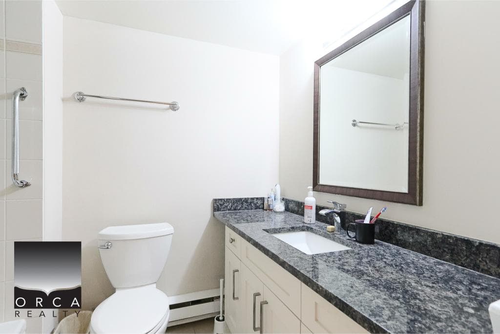 Clean bathroom with modern vanity, granite countertop, and white toilet, showcasing updated fixtures and neutral decor, ideal for Vancouver area home buyers and sellers.