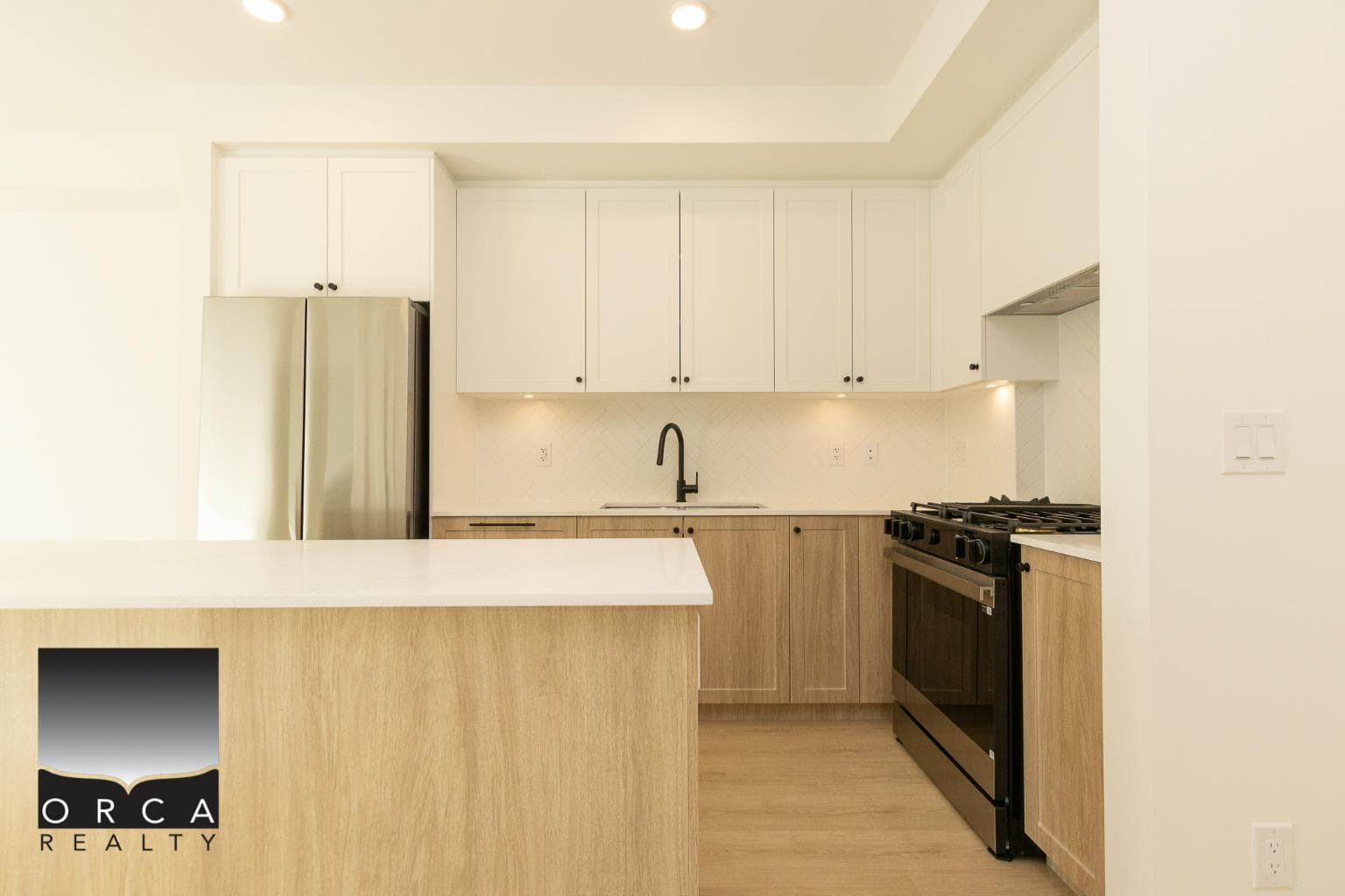 Modern kitchen with white and light wood cabinetry, stainless steel appliances, and a sleek black faucet, ideal for contemporary living and real estate marketing in Vancouver, BC.