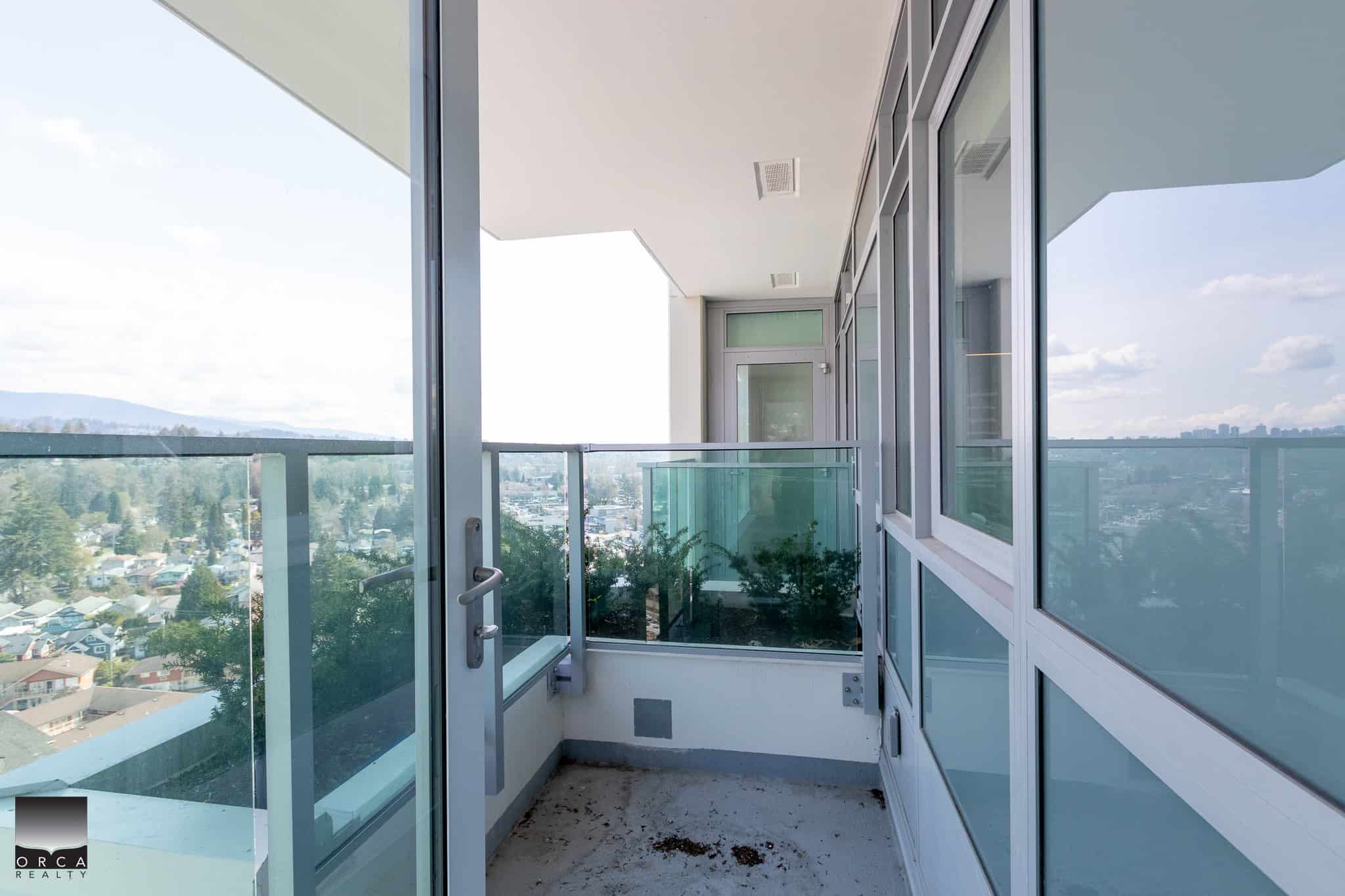 Spacious modern balcony with glass railings and panoramic city views in a contemporary condo building in Vancouver. Ideal for relaxing or entertaining outdoors.