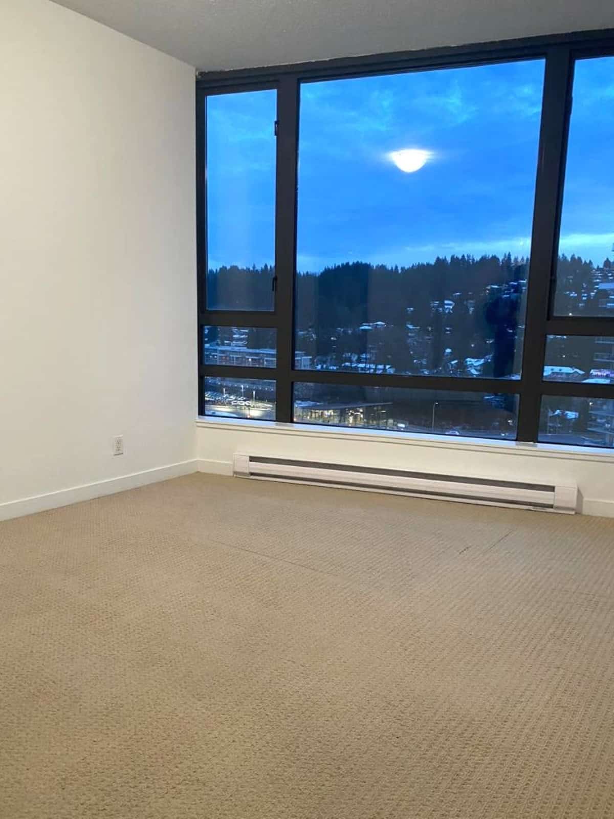 Bright empty apartment room with large floor-to-ceiling windows showcasing stunning mountain and city views, ideal for Vancouver real estate listings and property marketing.