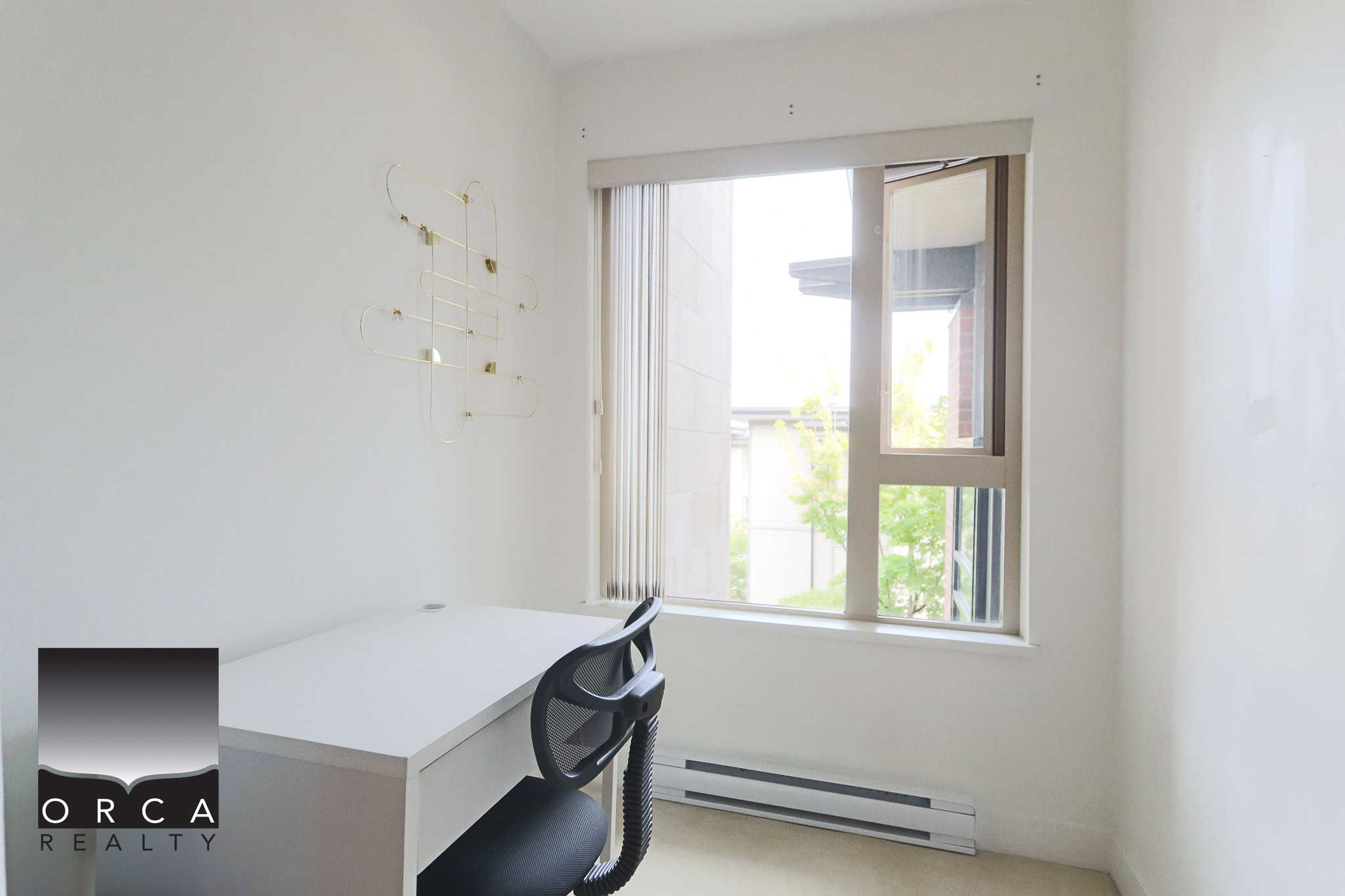 Bright home office with white walls, a minimalist desk, ergonomic chair, large window with natural light, and modern decor, perfect for productive work at Orca Realty Inc.