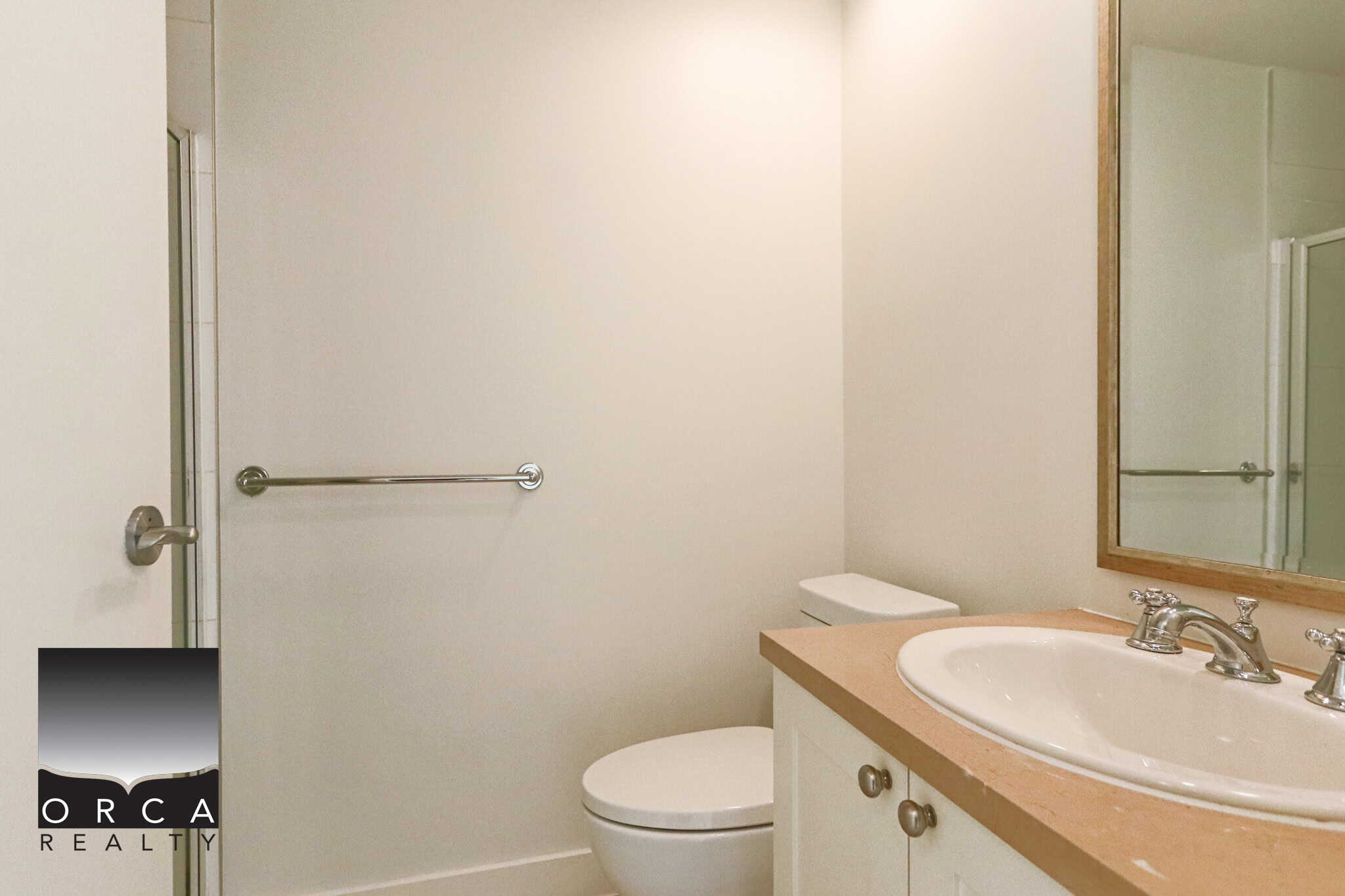 Bright and clean bathroom in North Vancouver featuring a white toilet, beige countertop, and a large mirror, perfect for a residential property at 203-170 W 1st Street.