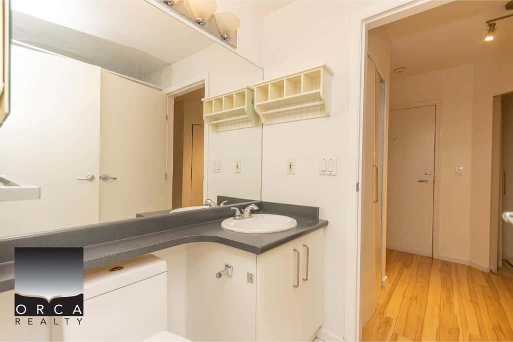 Bright and clean bathroom with white cabinets and a black countertop, ideal for Vancouver Island real estate listings and home inspections by Orca Realty Inc.