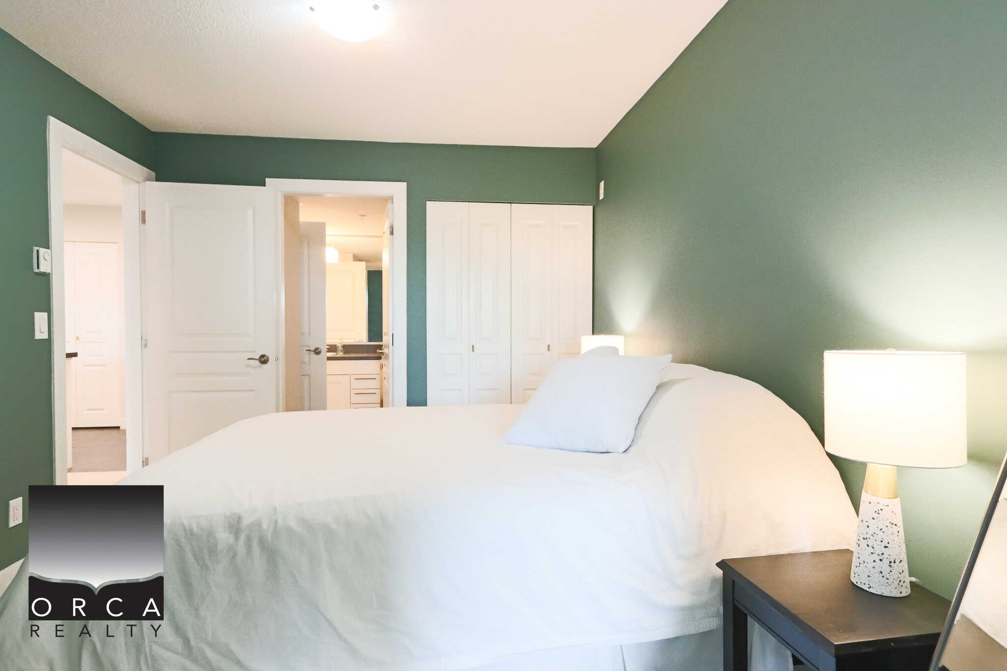 Contemporary bedroom with green accent wall, modern bedside lamps, and ample closet space, ideal for Vancouver homebuyers and real estate investors seeking stylish interior design.