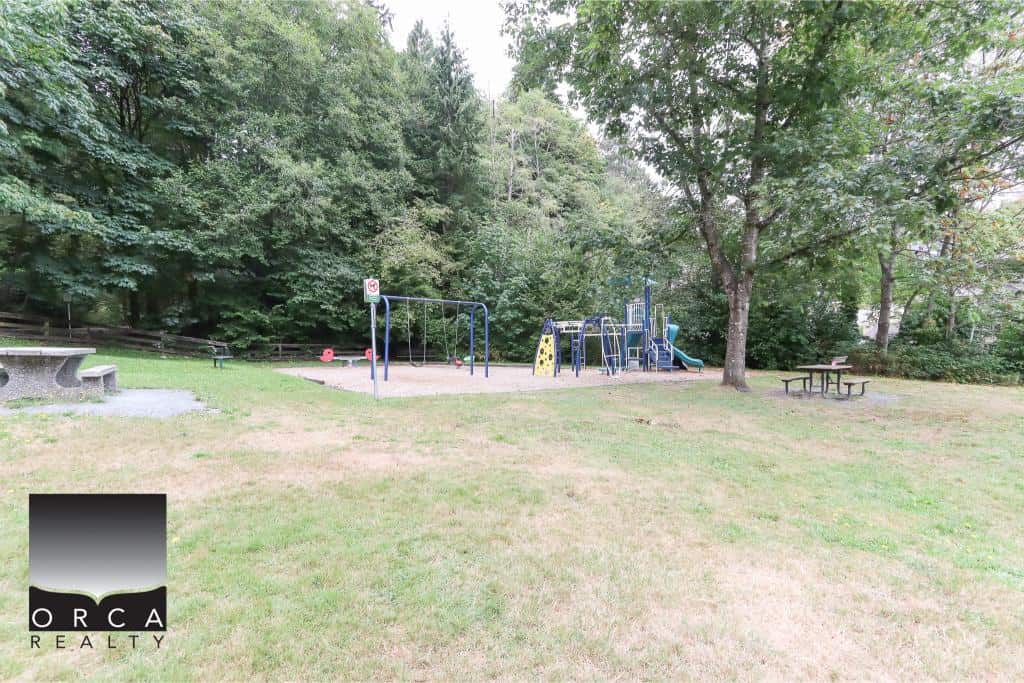 Colourful children's playground with slides, swings, and climbing structures in a park surrounded by lush green trees, ideal for family and community outdoor activities.