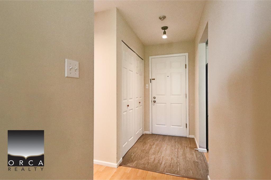 Bright and welcoming apartment entrance with clean white doors, beige walls, and hardwood flooring, ideal for Vancouver real estate buyers seeking modern condo or home options.