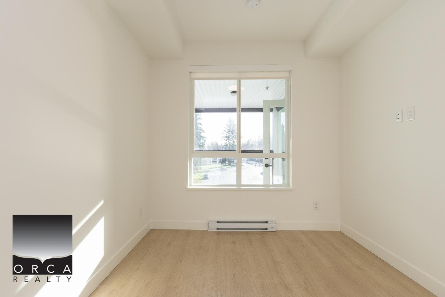 Bright empty room with large window and natural light in a modern home, showcasing quality interior design by Orca Realty Inc.