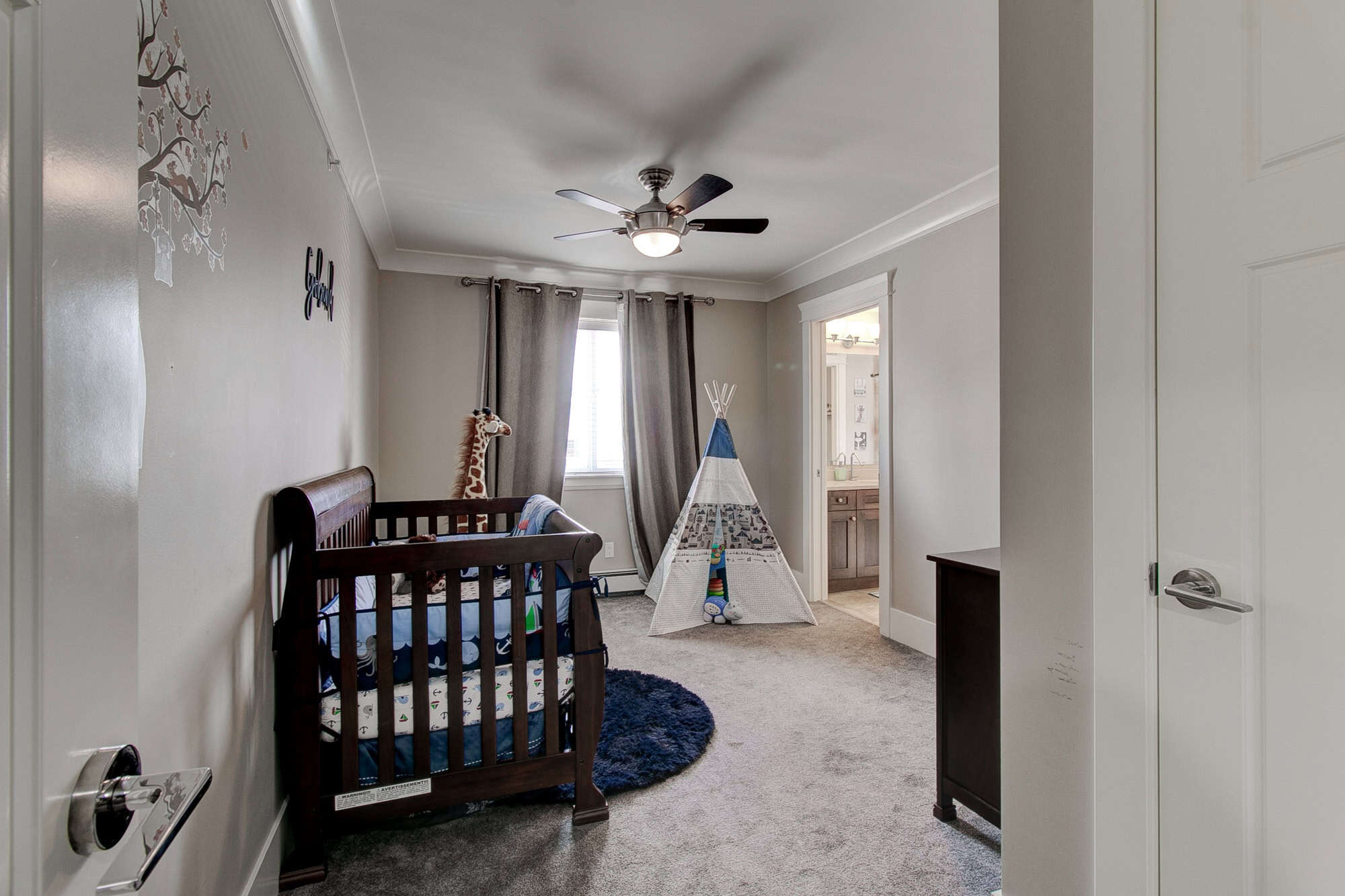 Bright children's bedroom with crib, tent play area, and modern decor, featuring a ceiling fan, neutral wall colours, and plenty of natural light, perfect for family living in the Vancouver area.