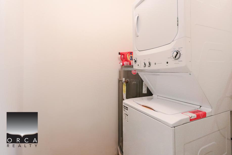 Stacked washer and dryer appliances in a laundry room, ideal for residential or rental property use in BC, showcasing Orca Realty Inc.'s real estate services.