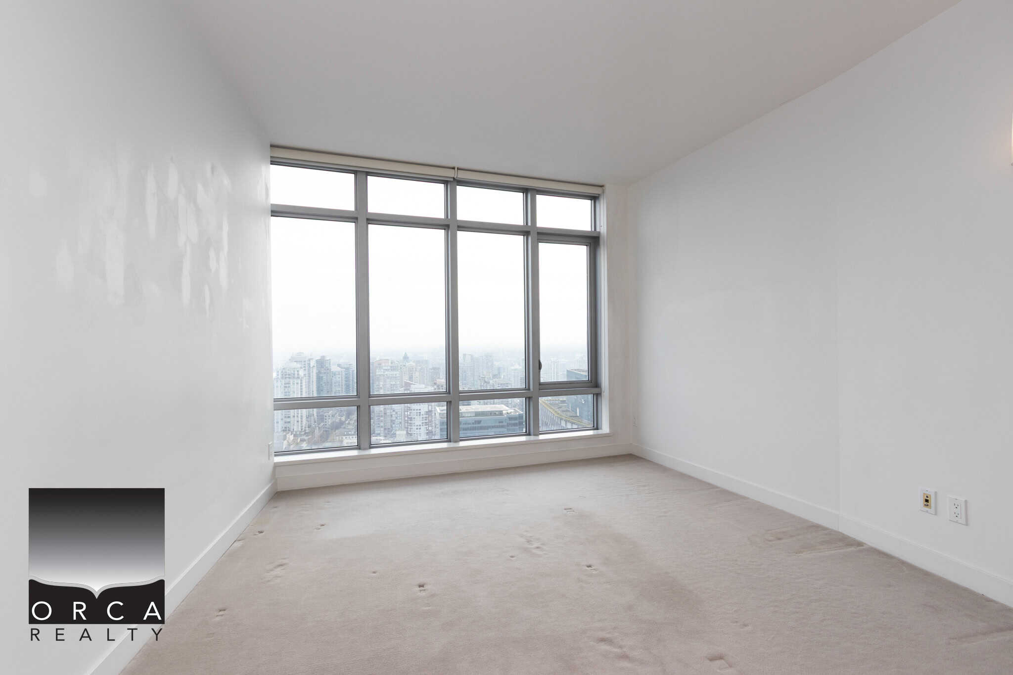 Bright high-rise condo bedroom with large floor-to-ceiling windows showcasing stunning city views, ideal for Vancouver real estate buyers seeking modern urban apartments.