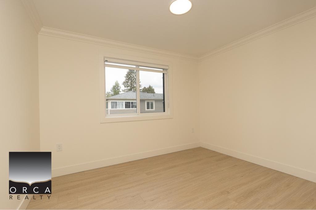 Bright empty bedroom with large window, white walls, and light wood flooring in a Vancouver-area home serviced by Orca Realty Inc., a trusted real estate agency in BC.