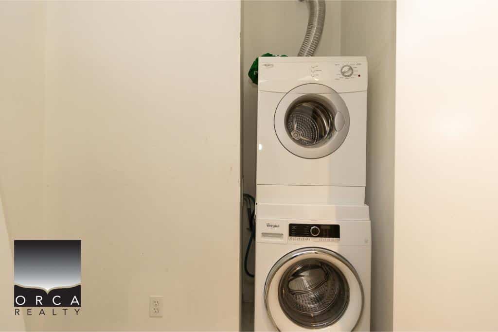 Stacked white washer and dryer in a laundry nook, showcasing modern appliances for residential or rental property image alt text.