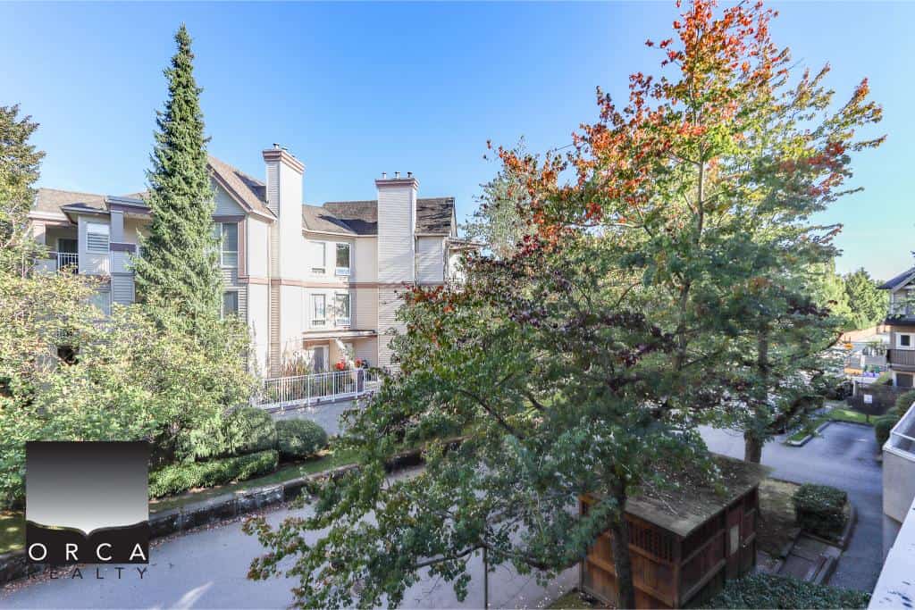 Lush green trees and modern residential apartments in a peaceful neighbourhood, showcasing Orca Realty Inc.'s commitment to prime property listings in BC.