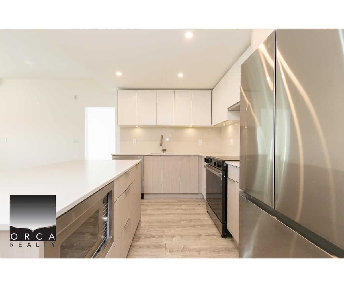 Contemporary modern kitchen with white cabinetry and stainless steel appliances, ideal for Vancouver Island real estate listings, featuring sleek design and functional layout for potential homebuyers.