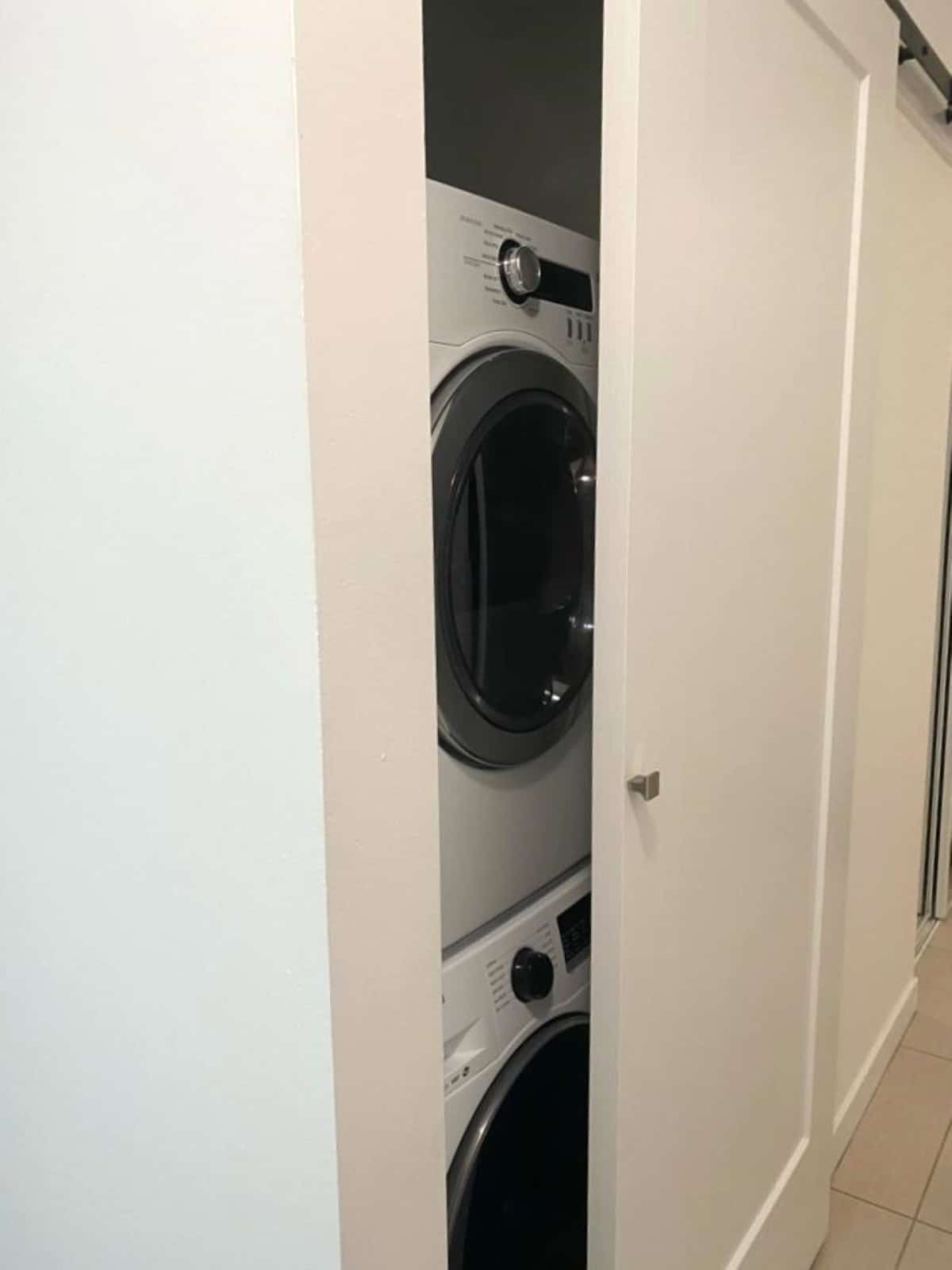 Stacked front-loading washer and dryer in a laundry closet, part of Orca Realty Inc. property listings, showcasing modern appliances and efficient space utilization for Vancouver Island homes.