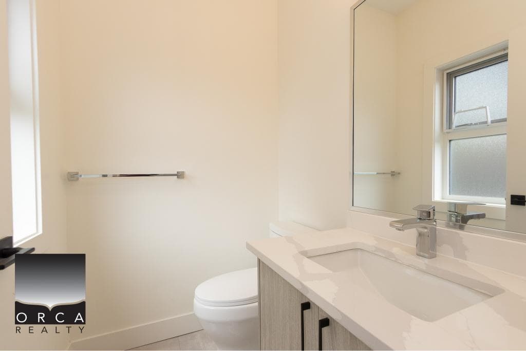 Modern bathroom with white fixtures, natural light from a frosted window, and neutral decor emphasizing home comfort and style for Vancouver real estate.