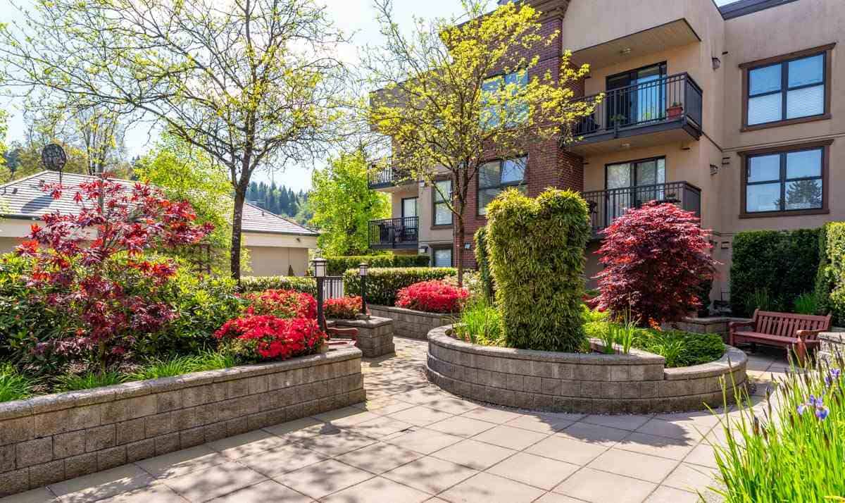Beautiful landscaped courtyard with lush greenery and colorful flowers at Orca Realty Inc. property. Perfect for relaxing and enjoying outdoor living in a vibrant community.