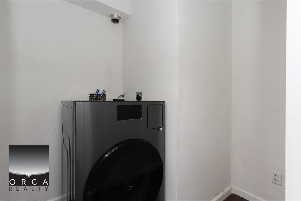Washing machine and laundry area in modern home, clean white walls, minimalistic design, ideal for property listings.
